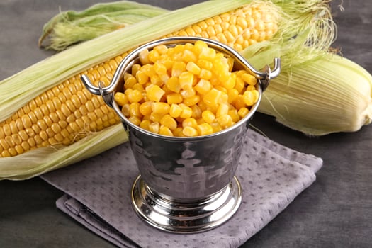 Corn in a metal bucket with a silver spoon photo