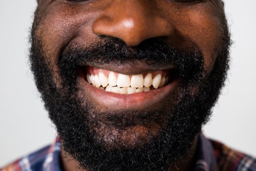 Close up portrait of perfect white teeth of a cheerful African American man smiling confidently on the gray background. photo