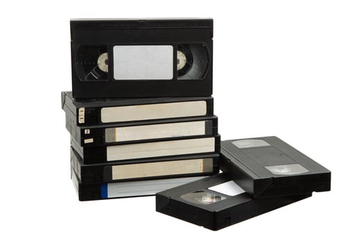 Stack of retro VHS tapes with blank labels on white photo