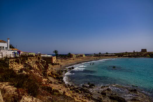 A coastal landscape reveals a serene beach with turquoise waters gently meeting the rocky shoreline photo