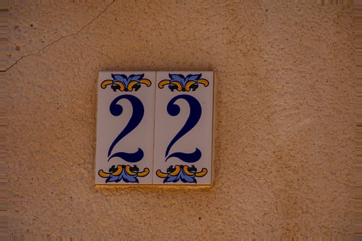 A ceramic tile with the number 22 is mounted on a textured, reddish-brown wall. photo