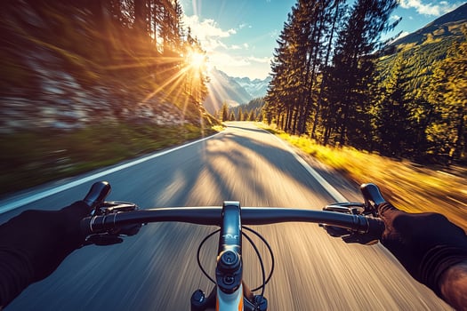 first person view of a cyclist riding at high speed on a narrow mountain road in warm sunset light, extreme sport concept, motion blur background photo