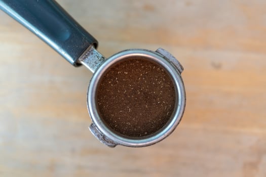 Ground coffee in portafilter on wood table photo