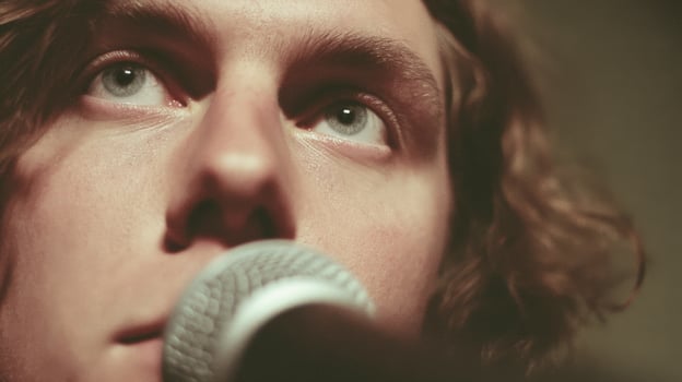 Close Up Portrait of a Young Male Musician Singing into a Microphone photo