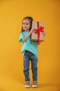 Present in, hands, gift box. Cute little girl is against yellow background photo