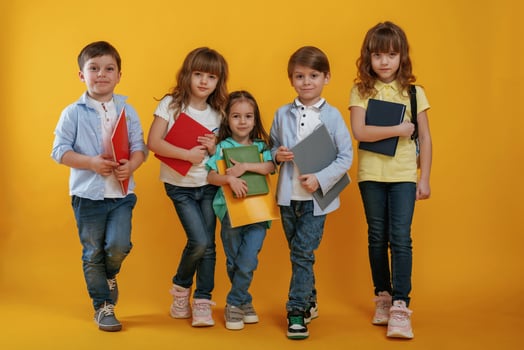 Notepads in hands, conception ,of education. Kids are together against yellow background photo