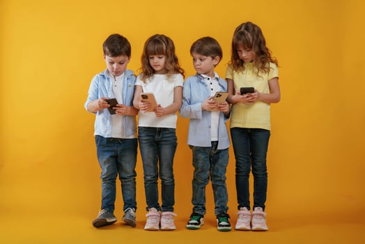 Using, smartphones. Kids are together against yellow background photo