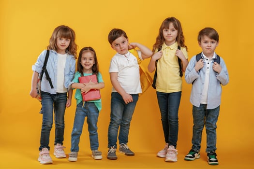 Standing and ,posing. Kids are together against yellow background photo
