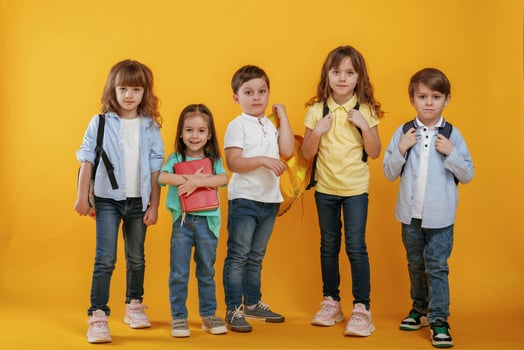 Standing, and posing. Kids are together against yellow background photo