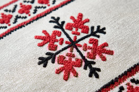 Ukrainian cross-stitch embroidery pattern featuring intricate red and black floral designs on a textured fabric background, showcasing traditional craftsmanship and cultural artistry photo
