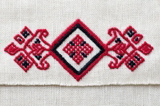 Ukrainian cross-stitch embroidery pattern featuring intricate red and black designs on a natural fabric background, showcasing traditional craftsmanship and cultural artistry photo