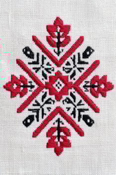 Ukrainian cross-stitch embroidery pattern featuring intricate floral and geometric designs in red and black on a light fabric background, showcasing traditional craftsmanship and cultural artistry photo