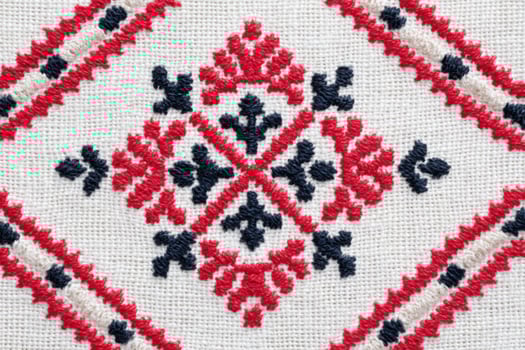 Ukrainian cross-stitch embroidery pattern featuring intricate geometric designs in red and black threads on a natural fabric background, showcasing traditional craftsmanship and artistic heritage photo