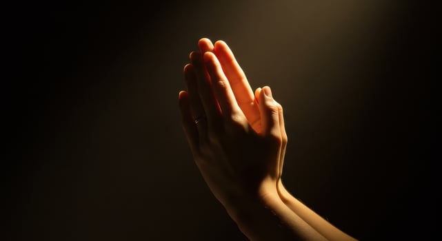 Woman hands pressed in prayer against a dark background, illuminated by soft, warm light, symbolizing faith, hope, and gratitude in a spiritual context. photo