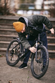 Man Inspects His Mountain Bike on a City Street photo