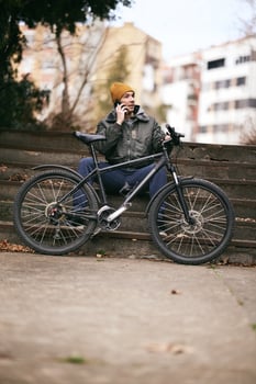Man Sitting Next to Bike Using Cell Phone photo