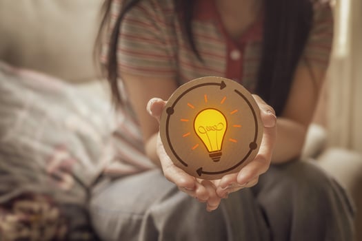 Woman holding a circle paper with light bulb icon. Represents new idea generation, design thinking, creative process and complex problem solving. photo