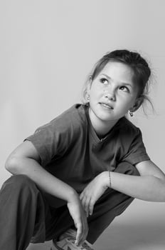 Monochrome close up of a girls face in studio lighting, eyes expressive, hair gently falling over her shoulder. The mood is serene and timeless. photo