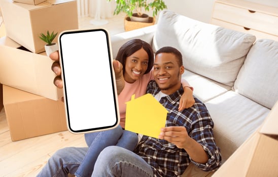 Affectionate black couple showing paper house and key to their home, sitting on floor of new property on relocation day. Positive African American tenants renting or purchasing new apartment photo