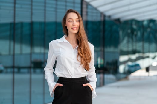 Confident businesswoman with long hair standing outside modern office photo