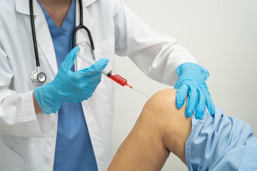 doctor inject Hyaluronic acid platelet rich plasma into knee of senior woman. photo