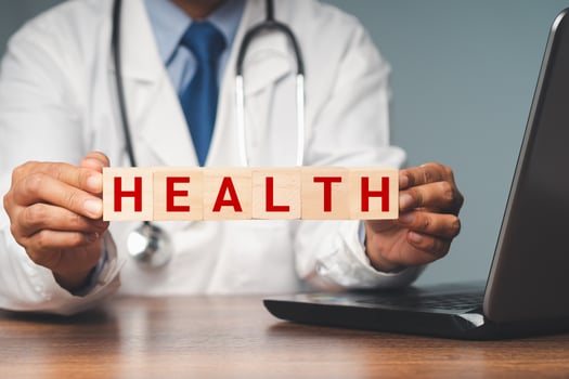 Doctor holding wooden cubes with the letters HEALTH while sitting in the hospital photo