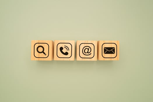 Top view of wooden cubes with symbols of a magnifying glass, mobile, address, and email on a green background. Flat Lay. photo