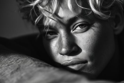 A dramatic black and white close-up portrait of a young woman with fair skin, freckles, and tousled blonde hair. photo