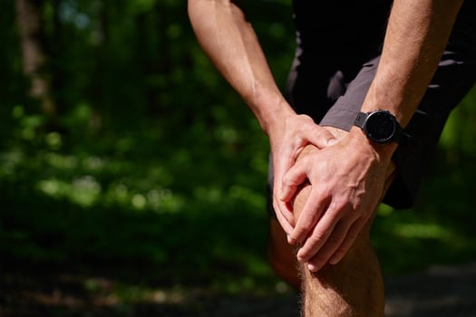 Runner holding knee in pain during workout in summer park photo
