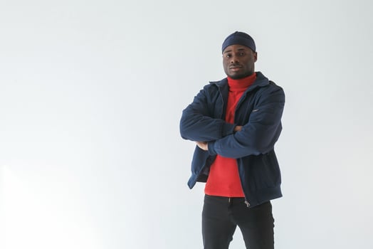 Posing with arms crossed. Black man,,, in ,cap is in the studio against white background photo