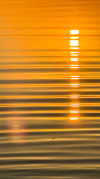 Golden sunset reflection on calm water surface with soft ripples creating a tranquil and serene ambiance capturing nature's beauty photo