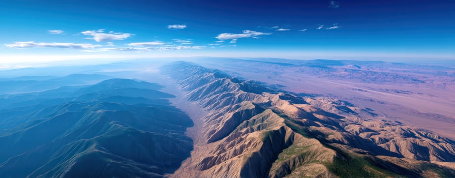 Aerial view of mountain range with rugged peaks and valleys under clear blue sky, showcasing natural beauty and vast landscape photo