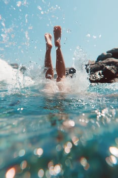 A playful summer scene of a persons legs sticking out of turquoise ocean water, mid-dive or upside down in the sea, captured from the water level. photo