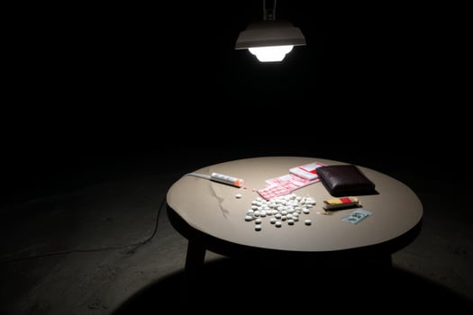 A table with pills, a lighter and a wallet photo