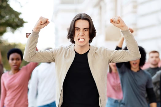 Young man leading multiracial group of people protesting against lockdown on the street, showing government attitude. Demonstrators making riot on the street, chanting slogans, need for money photo