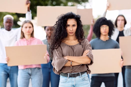 Active pretty brunette young woman leading a group of demonstrators on the street. International diverse group of people with blank placards protesting for human or animal rights and against racism photo