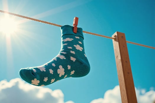 A sock hanging on a clothesline with the sun in the background photo