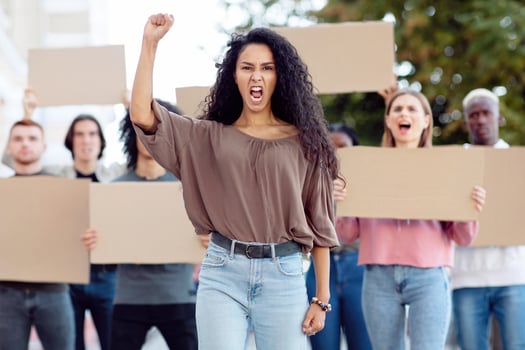 Mixed race emotional young woman leading a group of demonstrators on the street. International diverse group of people with blank placards protesting for human rights and against racism photo