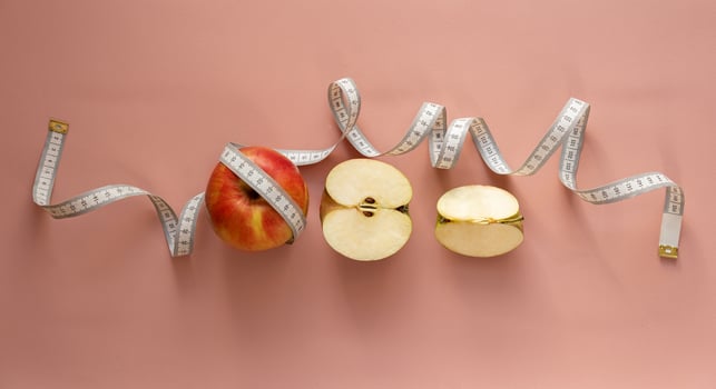 White measuring tape and red apple, diet, weight loss concept, healthy eating. Soft focus. photo