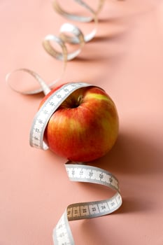 White measuring tape and red apple, diet, weight loss concept, healthy eating on background for text. photo