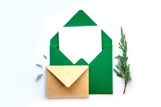 Elegant green envelopes with a blank card and a pine sprig on a white background for a seasonal greeting photo