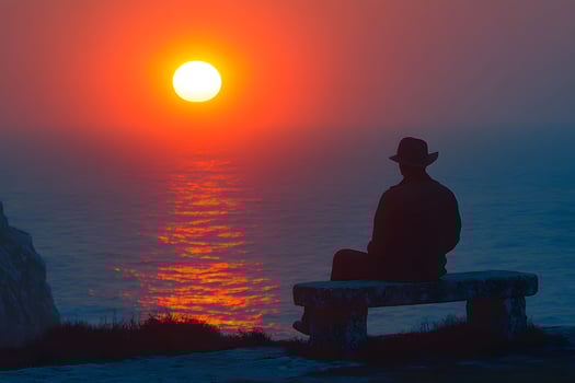 Solitude at Sunset Man Reflecting by the Ocean on a Stone Bench photo