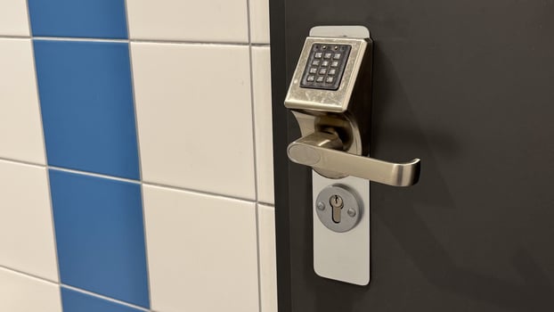 Modern electronic door lock with keypad on a dark door next to blue and white tiled wall showcasing advanced security technology photo