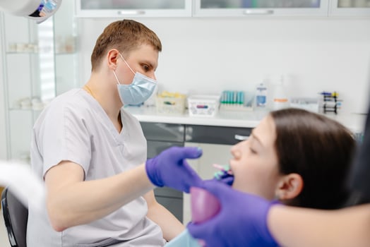 Dentist applying dental mold to young patient's teeth in office photo