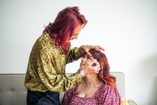 Non-binary make-up artist applying eyeliner to friend celebrating body positivity and sexual diversity photo