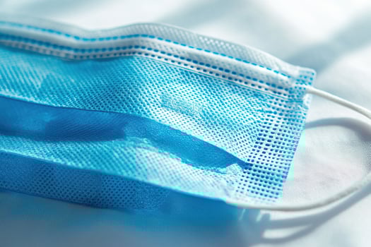 Close-up blue medical face mask on white surface. concept health protection, hygiene, and the prevention of seasonal illnesses and epidemics in simple, minimalistic setting photo