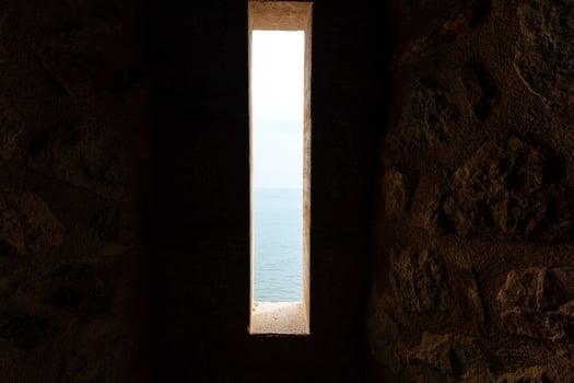 Dimly lit ancient stone corridor with light streaming through an open door, evoking mystery and exploration. photo