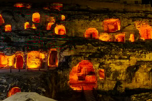 Illuminated Historic Caves with Vibrant Warm Lights at Night photo