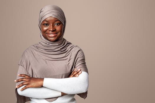 Portrait Of Beautiful Black Muslim Woman In Hijab Posing With Folded Arms Over Light Background In Studio, Confident Religious African Lady In Headscarf Looking And Smiling At Camera, Copy Space photo