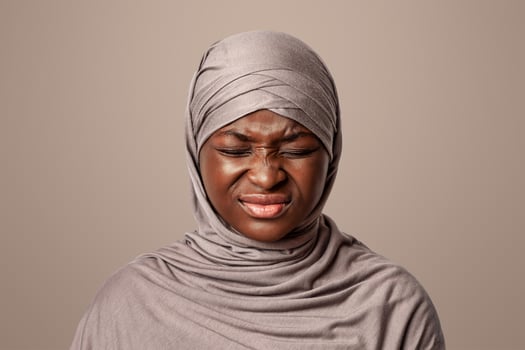 Negative Emotion. Portrait Of Irritated Black Muslim Lady In Hijab Grimacing With Displeased Face Expression Over Light Studio Background, Closeup Of Annoyed African Woman In Headscarf, Copy Space photo